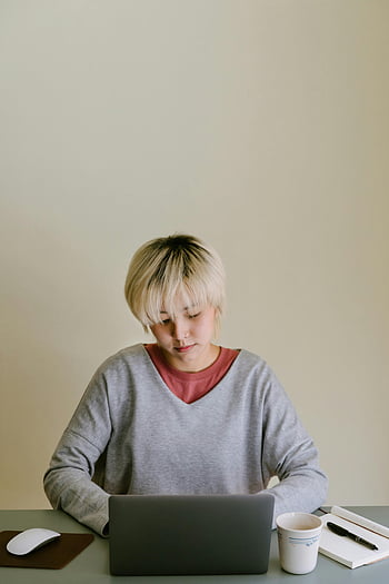 geconcentreerde vrouw, laptop gebruiken, binnenshuis studeren, minimale afleiding, jonge vrouw, gefocust, binnenstudie, laptop werk, opstelling van het bureau, koffiemok, notitieboekje