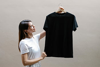 Giovane donna sorridente, maglietta casual, muro grigio, donna allegra, maglietta bianca, maglietta nera, appendiabiti, sfondo grigio, moda, capi di abbigliamento, stile