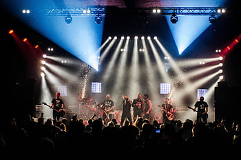 live -yhtyeen esitys, lavavalot, suuri yleisö, energinen suorituskyky, elävä vaihe, konsertti, yhtye, näyttämö, elävää musiikkia, konserttivalaistus, yleisön sitoutuminen