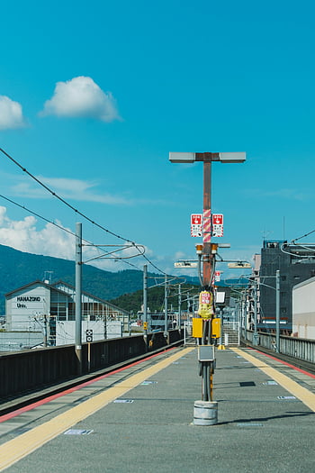 empty train platform, Hanazono Station, deserted platform, clear sky, urban tranquility, train station, Japan, railway station, blue sky, yellow lines, mountain view