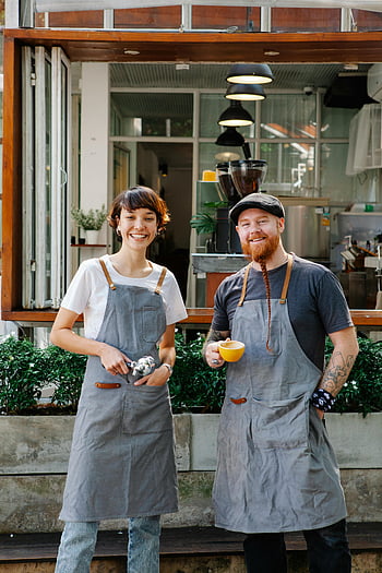 cheerful baristas, aprons, coffee house, modern café, coffee cups, friendly atmosphere, smiling baristas, outside café, coffee shop, barista uniforms, modern coffee shop