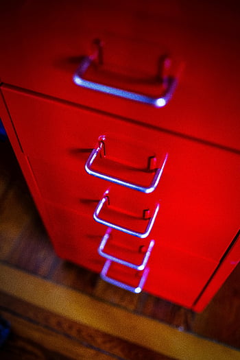red storage cabinet, chrome handles, vibrant modern design, illuminated red, bright red, close-up, modern furniture, contemporary design, red cabinet, chrome accents, red drawer unit