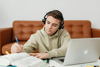 Chlapec dělá domácí úkoly, poslouchání hudby, dospívající chlapec, sluchátka, zaměřené studium, laptop, uvnitř, domácí práce, studovat, hudba