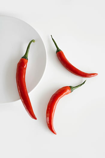 raw chili peppers, vibrant red chili peppers, minimalist white background, spicy flavor, close-up chili peppers, white surface, red peppers, minimalist photography, food photography, chili pepper images, white plate