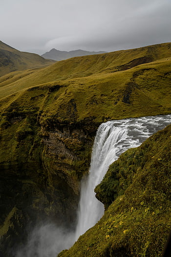 Skogafoss Waterfall, Iceland, Rangárþing eystra, stunning view, cascading waterfall, natural landscape, green hills, scenic beauty, travel destination, outdoor adventure, icelandic nature