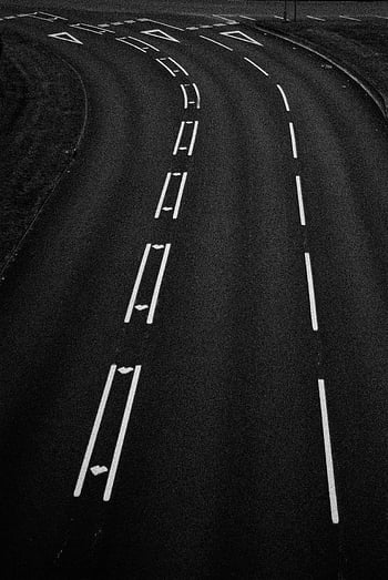 Graustufen -Luftaufnahme, gekrümmte Straße, Spurmarkierungen, abstrakte Linien, Asphaltboden, Straßenschilder, Luftaufnahmen, Schwarz und weiß, Strassenmarkierungen, Verkehrsschilder, Straßengestaltung