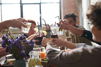 Bere di gruppo, impostazione interna, Amici toast, Atmosfera accogliente, cibo e fiori, ambiente caldo, ritrovo sociale, bevande celebrative, pranzo informale, Celebrazione del gruppo, Celebrazione indoor