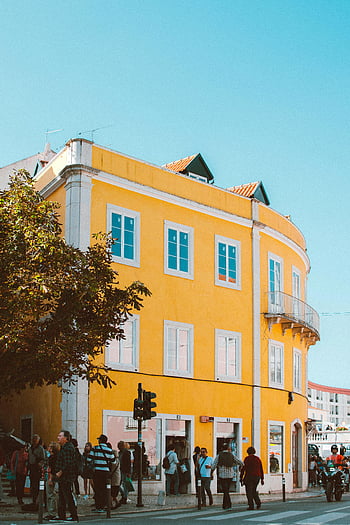 Lissabon, gelbes Gebäude, Bunte Straßenszene, Fußgänger, blauer Himmel, lebendige Architektur, städtische Landschaft, europäische Stadt, sonniger Tag, Strassenfotografie, Reiseziel