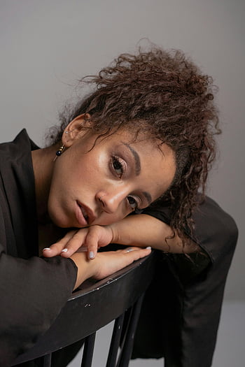 mujer de pelo rizado, top negro, retrato de primer plano, pelo rizado, apoyado en la silla, Expresión pensativa, Mujer con pelo rizado, ropa negra, fotografía de retrato, foto de estudio, fotografía de interior