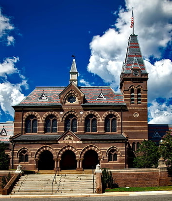 Gallaudet University, historic building, clear blue sky, cumulus clouds, brown black and grey building, majestic architecture, university campus, outdoor scene, educational institution, architectural landmark, daytime photo