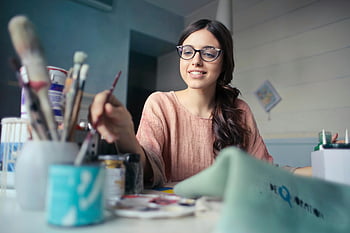 Kobieta artystka, Brązowa koszula z długim rękawem, okulary, pędzel malarski, kreatywne studio, młoda kobieta, obraz, przybory do sztuki, ustawienie artystyczne, sztuka wnętrz, uśmiechnięty artysta