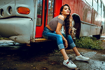 Kobieta siedzi na schodach autobusu, stylowa kobieta, swobodne dżinsy, scena miejska, Krok autobusowy, siedzący fenzynie, czerwony autobus, Białe tenisówki, moda miejska, Zwyczajny outfit, styl uliczny