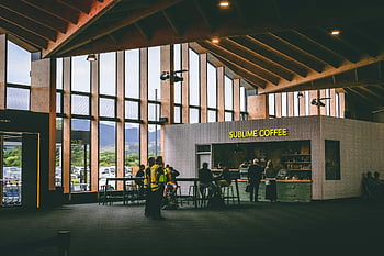 Erhabener Kaffee, modernes Café, große Fenster, Menschen, die Getränke genießen, Café im Innenbereich, Coffee-Shop-Interieur, Café-Design, Café-Atmosphäre, Coffeeshop-Kunden, Coffee Shop Ambiente, Café -Shop -Einstellung