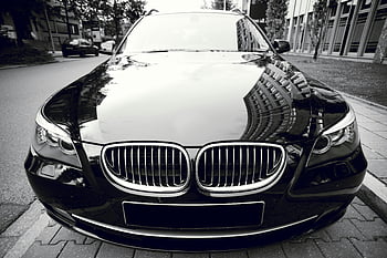 BMW, car parked, front view, shiny black, luxury sedan, city buildings reflection, elegance, style, urban setting, vehicle exterior, automotive design