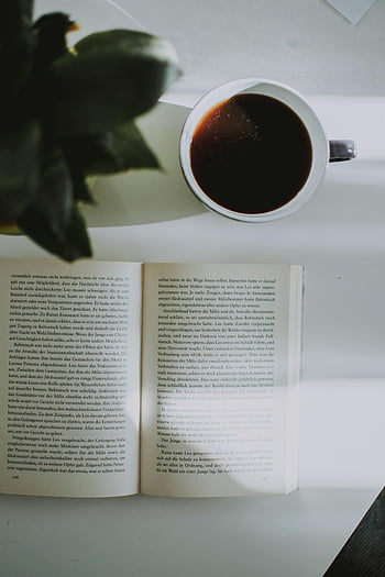 قهوة،  كتاب،  طاولة مضاءة،  قراءة مريحة،  المشهد الداخلي،  قهوة سوداء،  كتاب مفتوح،  جلسة القراءة،  إعداد الجدول،  ضوء طبيعي،  جو مريح