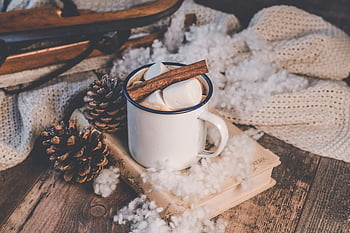 white ceramic mug, cozy winter scene, hot chocolate, cinnamon, marshmallows, rustic sled, pine cones, winter decor, hot cocoa, winter atmosphere, festive setting