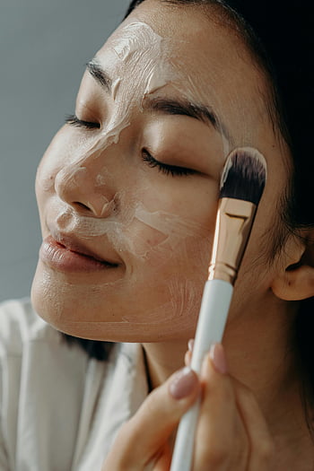 Asian woman, skincare routine, facial cream, makeup brush, healthy skin, close-up, applying cream, eyes closed, beauty, skincare, facial treatment