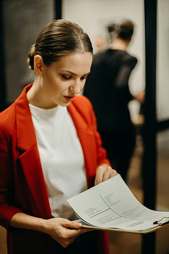 Žena čtení papírů, Zaměřená žena, Červený sako, zkoumání dokumentů, obchodní koncentrace, profesionalitu, Nastavení kanceláře, Profesionální oděv, podnikatelka, Přezkum dokumentu, pracovní prostředí