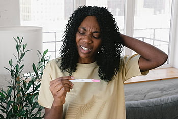 femeie africană americană, test de sarcina, expresie îngrijorată, Setare interioară, par cret, haine casual, Mediul de origine, îngrijorare pentru sănătate, moment emoțional, spatiu personal, test medical