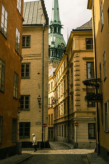 Stockholm Street -Szene, historische Architektur, Klassische Gebäude, gehende Person, malerische Straße, Kopfsteinpflasterstraße, europäische Stadt, städtische Landschaft, alte Stadt, Kirchturm, Straßenkreuzung