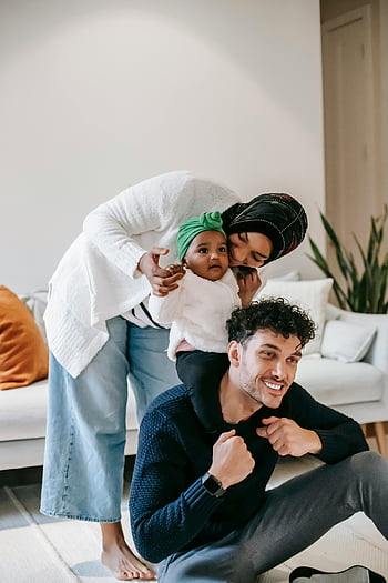 Multirassische Familie, Süße Tochter, glückliche Familie, Verspielter Moment, gemütliches Wohnzimmer, Familienzeit, Zuhause, Freude Familie, Multirassische Eltern, Kleine, familiäre Bindung