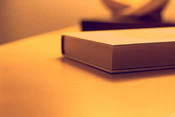 libro chiuso, Fotografia minimalista, tavolo di legno, illuminazione calda, Studia temi, temi della letteratura, colpo del primo piano, fotografia del libro, impostazione interna, focalizzazione morbida, Atmosfera accogliente