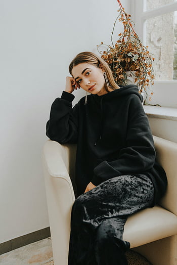 kobieta siedzi, okno, czarna bluza z kapturem, zrelaksowany klimat, ustawienie wewnętrzne, wygodny, Zwyczajny styl, wystrój domu, naturalne światło, Przytulna atmosfera, fotel