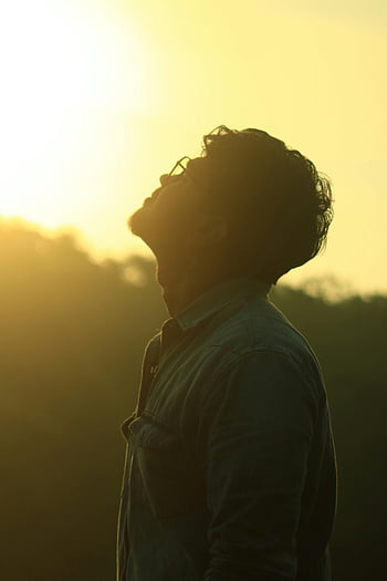 man looking up, vibrant sunset, contemplative man, silhouette photography, sunset silhouette, outdoor photography, peaceful moment, nature backdrop, golden hour, reflective pose, serene scene