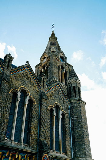 Středověký cihlový kostel, gotický kostel, ozdobená věže, čisté nebe, architektonické detaily, slunečný den, fasáda, majestátní církev, složitý design, cihlová architektura, kostelní věž