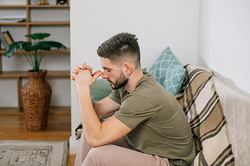 mężczyzna siedzący na kanapie, splecione ręce, przytulny salon, młody człowiek, przemyślana poza, ustawienie wewnętrzne, Wygodna sofa, wystrój domu, casualowy strój, swobodna atmosfera, fotografia wnętrz