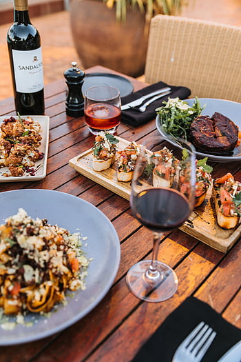gourmet dishes, wine, wooden table, refined dining, culinary enthusiasts, sophisticated table decor, food photography, dining setting, wine glass, table setting, outdoor dining