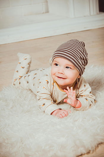 smiling baby, striped beanie, fluffy rug, indoor photo, baby innocence, cute baby, white mat, baby lying, baby smile, baby outfit, baby photography