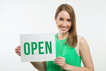 woman holding open sign, cheerful woman, green dress, business use, open sign, smiling woman, promotional image, welcoming gesture, business signage, white background, professional photo