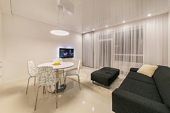 fekete szövet kanapé, kerek fehér asztal, modern bútorok, elegáns világítás, karcsú nappali, elegáns belső, kortárs design, fehér étkezőszékek, fekete oszmán, fehér függönyök, minimalista dekoráció