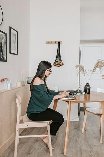 Žena vzdálená pracovníka, psaní na notebooku, Minimalistický dřevěný stůl, Mladá žena pracuje, domácí kancelář, zaměřeno na práci, minimalistický dekor, vnitřní pracovní prostor, příležitostný pracovní oděv, Útulné domácí prostředí, Moderní nastavení domácí kanceláře