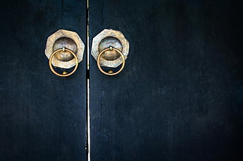 closed black wooden door, vintage wooden doors, brass circular handles, traditional design elements, close-up doors, black door, brass handles, wooden door handles, vintage doors, traditional doors, circular door handles