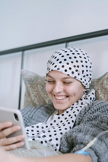 smiling woman, white and black polka dot hijab, using smartphone, bed, polka dot scarf, happy, indoor, casual, technology, relaxation, comfort