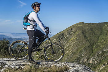 man with white shirt, riding bicycle, mountain biking, scenic rocky landscape, clear blue sky, adult cyclist, mountain bike, outdoor adventure, nature photography, cycling gear, helmet and sunglasses