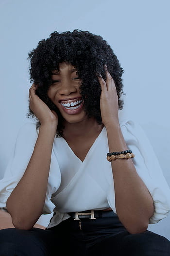 femme noire, cheveux bouclés, en riant, heureux, de bonne humeur, Afro-américain, souriant joyeusement, réglage du studio, bracelet, chemise blanche, pantalon noir