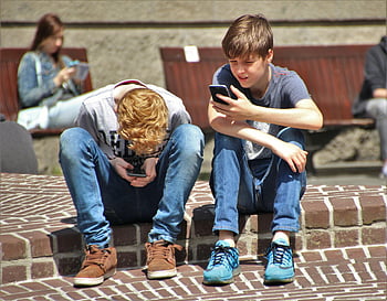 teenageři, smartphony, venkovní posezení, moderní technologie, během dne, zaměřená pozornost, ležérní oblečení, veřejný prostor, sociální interakce, Digitální zapojení, městském prostředí