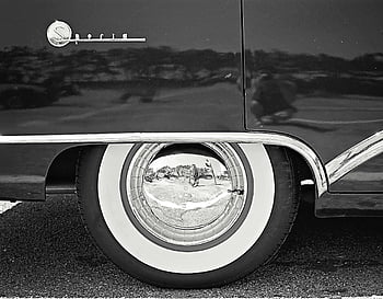 black and white car wheel, vintage car, whitewall tire, chrome hubcap, close-up, reflective hubcap, classic car, black and white photography, car tire, vintage automobile, chrome rim