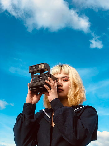 vaalea nainen, lyhyet hiukset, vintage-kamera, kirkkaan sininen taivas, polaroidikamera, Ulkokuvaus, Rento asu, kirkas taivas, päiväkohta, nainen valokuvaaja, pikakamera