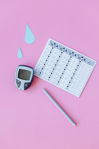 blood glucose monitoring, diabetes management, glucose meter, recording sheet, chart, pen, pink background, top view, health tracking, medical device, blood sugar
