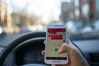 rozrušené řízení, textových zpráv během jízdy, Použití smartphonu, uvnitř vozidla, Řízení města, bílý smartphone, osoba hospodářství telefon, Interiér automobilu, využití technologie, městská jízda, rozptýlení řidiče
