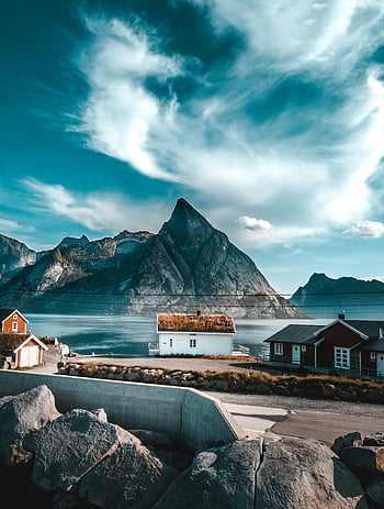 Norwegian village, sea, mountains, dramatic sky, brown and white house, body of water, picturesque view, coastal scenery, rural landscape, natural beauty, scenic backdrop
