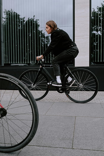 man in black jacket, black bicycle, urban setting, modern city life, transportation, black pants, cityscape, bicycle rider, urban transportation, street scene, city dweller