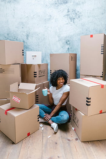 žena hospodářství pohár, sedí na podlaze, obklopeno kartonovými krabicemi, Přepravní boxy, usmívající se žena, afro vlasy, džbánek, uvnitř, pohyblivé krabice, rozbalení, domovní dekorace