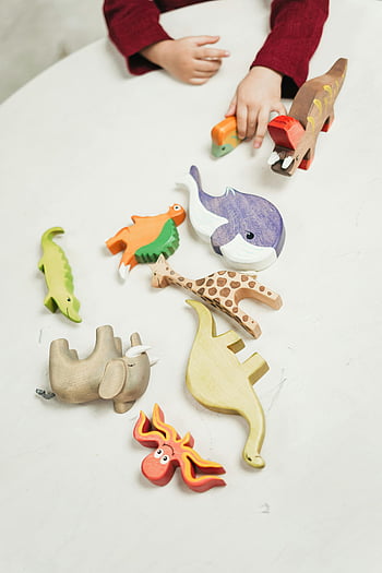 Holzspielzeugtiere, Buntes Holzspielzeug, spielendes Kind, Indoor-Spiel, weißer Tisch, Holzspielzeug, Vielfalt von Spielzeug, Innenspielzeug, tierisches Spielzeug, Kinderspielzeug