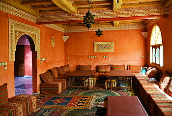 interni marocchini, soggiorno rosso, arredamento tradizionale, modelli vibranti, posti a sedere accoglienti, stanza illuminata dal sole, design marocchino, arredamento culturale, soffitto ornato, tappeti a motivi geometrici, tavoli di legno