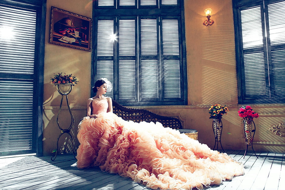 bride, luxurious gown, sunlit room, elegance, woman sitting, bench near window, wedding dress, indoor setting, floral arrangements, vintage decor, natural light